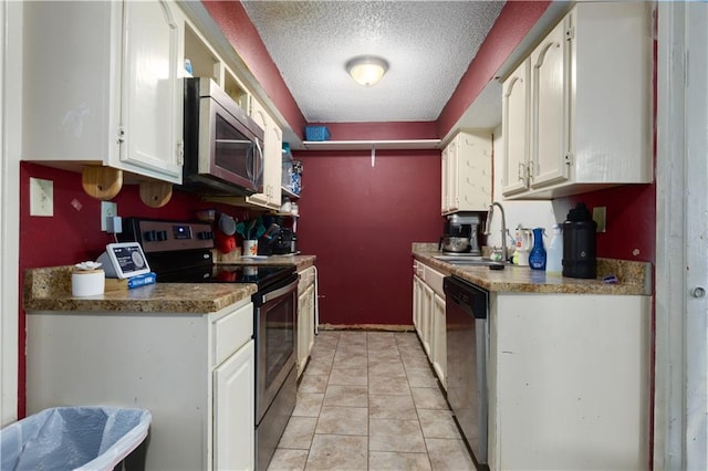 2716 S 52nd St, Kansas City, KS 66106 - kitchen with stainless steel appliances, a textured ceiling, white cabinets, and light tile patterned floors