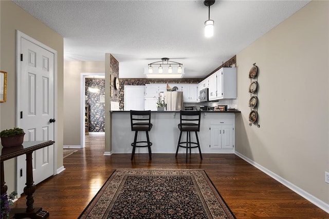 5817 Park Cir, Shawnee, KS 66216 - kitchen with freestanding refrigerator, dark wood-type flooring, stainless steel microwave, dark countertops, and a peninsula