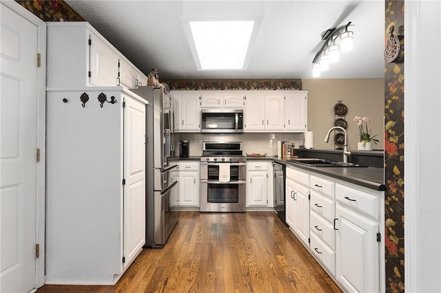 5817 Park Cir, Shawnee, KS 66216 - kitchen featuring stainless steel appliances, dark countertops, dark wood-style floors, white cabinets, and backsplash