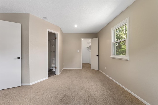 7421 NW 76th Ter, Kansas City, MO 64152 - unfurnished bedroom featuring carpet floors, a spacious closet, connected bathroom, a textured ceiling, and recessed lighting