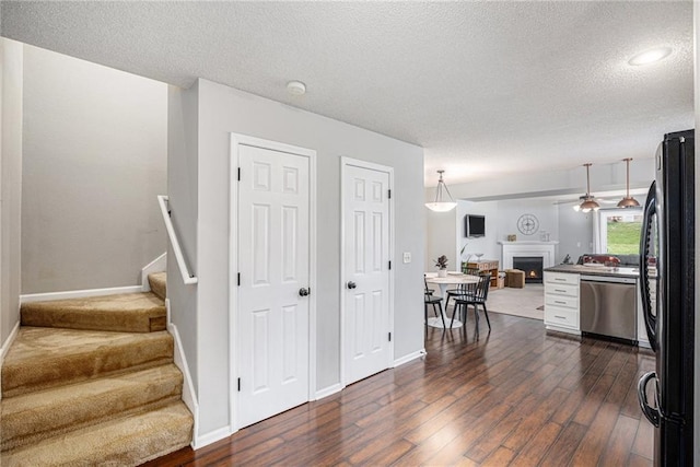 9583 N Main St, Kansas City, MO 64155 - stairway featuring a warm lit fireplace, wood finished floors, and a textured ceiling