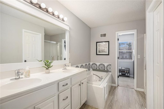 9583 N Main St, Kansas City, MO 64155 - bathroom with a tub with jets, double vanity, a textured ceiling, wood finished floors, and an enclosed shower