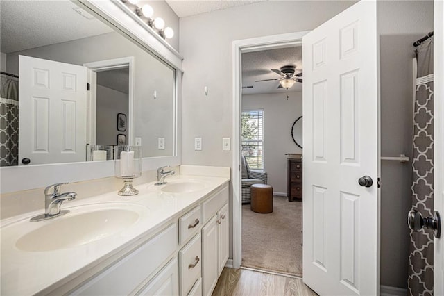 9583 N Main St, Kansas City, MO 64155 - bathroom featuring a textured ceiling, double vanity, ceiling fan, and wood finished floors