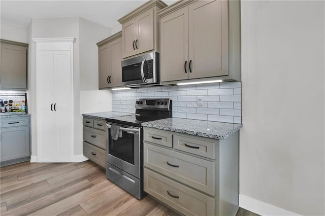 307 S Wilson St, Archie, MO 64725 - kitchen with stainless steel appliances, light wood-style floors, backsplash, light stone counters, and gray cabinets