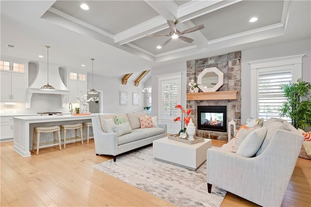 2210 W 73rd St, Prairie Village, KS 66208 - living area with light wood-style floors, ceiling fan, plenty of natural light, a stone fireplace, and beamed ceiling