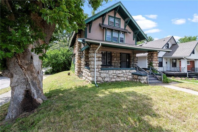 3544 College Ave, Kansas City, MO 64128 - view of front of home featuring covered porch, a front yard, stone siding, and stucco siding