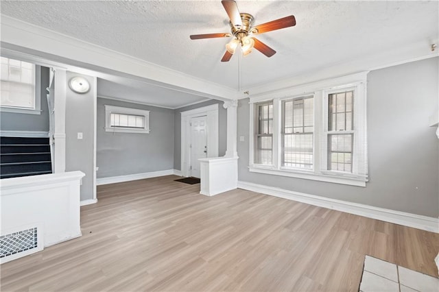 3544 College Ave, Kansas City, MO 64128 - unfurnished living room featuring ceiling fan, stairs, wood finished floors, a textured ceiling, and plenty of natural light