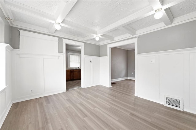 3544 College Ave, Kansas City, MO 64128 - unfurnished bedroom featuring a decorative wall, coffered ceiling, light wood-style flooring, beam ceiling, and a textured ceiling