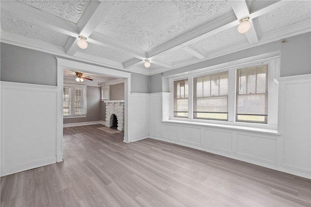 3544 College Ave, Kansas City, MO 64128 - unfurnished living room with a ceiling fan, coffered ceiling, a wainscoted wall, a decorative wall, and a fireplace with flush hearth