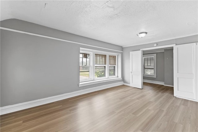 3544 College Ave, Kansas City, MO 64128 - unfurnished bedroom with light wood-type flooring and a textured ceiling