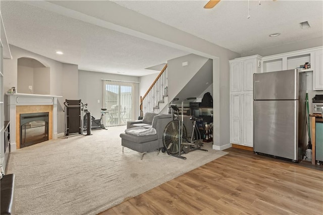 820 Peach Tree Ln, Blue Springs, MO 64064 - living area with a tiled fireplace, wood finished floors, stairs, a ceiling fan, and recessed lighting