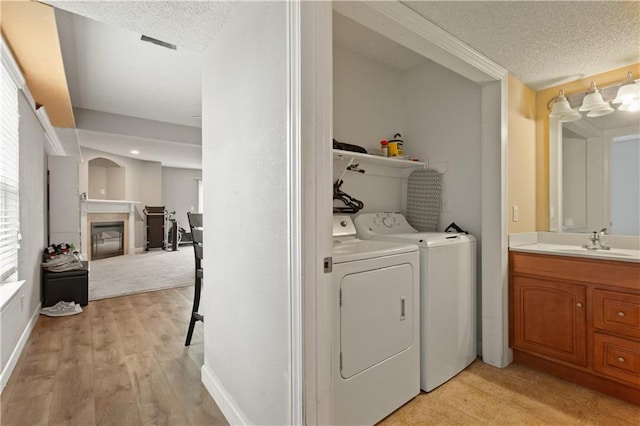 820 Peach Tree Ln, Blue Springs, MO 64064 - washroom featuring washer and dryer, a textured ceiling, a tile fireplace, and light wood-type flooring