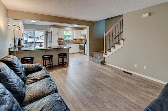 3524 NE Austin Dr, Lees Summit, MO 64064 - living room featuring light wood-style flooring, a textured ceiling, and stairway