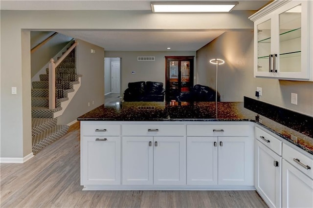 3524 NE Austin Dr, Lees Summit, MO 64064 - kitchen with a peninsula, dark stone countertops, glass insert cabinets, and white cabinetry