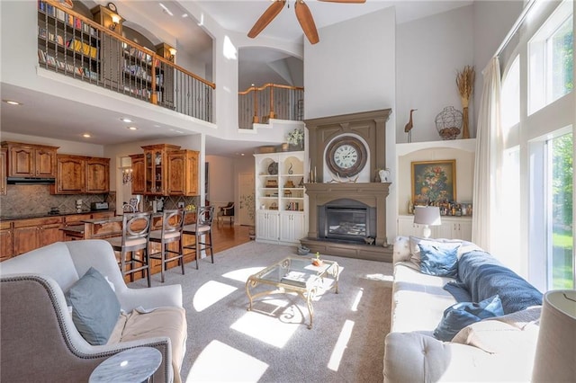 3013 S Granite Ave, Blue Springs, MO 64015 - living room with a towering ceiling, a ceiling fan, light colored carpet, recessed lighting, and a glass covered fireplace