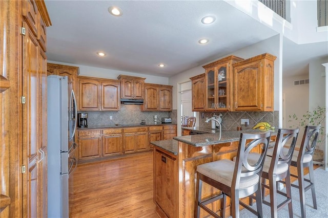 3013 S Granite Ave, Blue Springs, MO 64015 - kitchen featuring freestanding refrigerator, brown cabinetry, a peninsula, under cabinet range hood, and recessed lighting