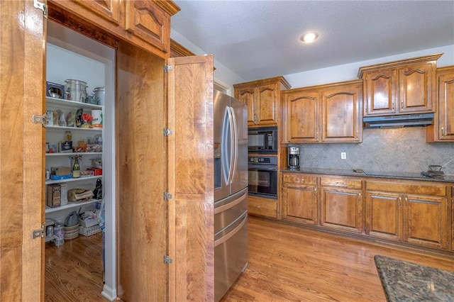 3013 S Granite Ave, Blue Springs, MO 64015 - kitchen featuring black appliances, under cabinet range hood, light wood-type flooring, brown cabinetry, and recessed lighting