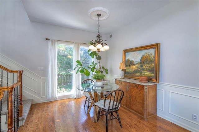 3013 S Granite Ave, Blue Springs, MO 64015 - dining space featuring a wainscoted wall, a decorative wall, a chandelier, stairway, and wood finished floors
