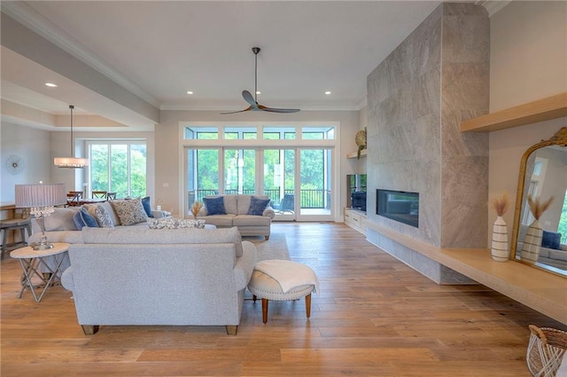7736 N Donnelly Ave, Kansas City, MO 64158 - living room featuring ornamental molding, light wood-type flooring, recessed lighting, a tiled fireplace, and ceiling fan