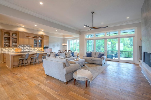 7736 N Donnelly Ave, Kansas City, MO 64158 - living area featuring crown molding, recessed lighting, light wood-style flooring, a fireplace, and a ceiling fan