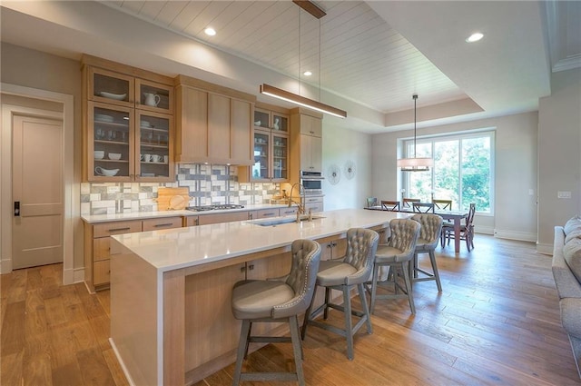 7736 N Donnelly Ave, Kansas City, MO 64158 - kitchen featuring light countertops, light wood-type flooring, decorative backsplash, a tray ceiling, and recessed lighting