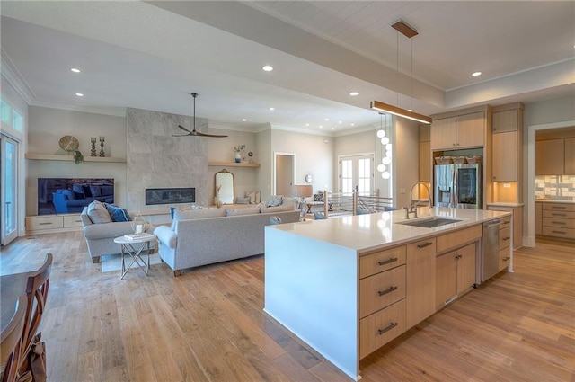 7736 N Donnelly Ave, Kansas City, MO 64158 - kitchen featuring light brown cabinetry, ornamental molding, light wood-style flooring, appliances with stainless steel finishes, and a ceiling fan