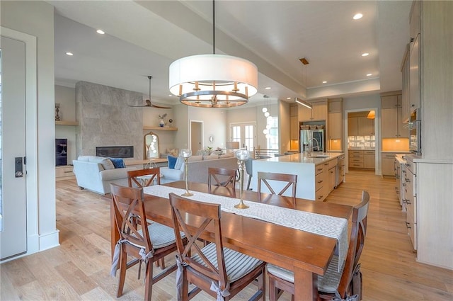 7736 N Donnelly Ave, Kansas City, MO 64158 - dining room with light wood-style flooring, a tile fireplace, ceiling fan, and recessed lighting