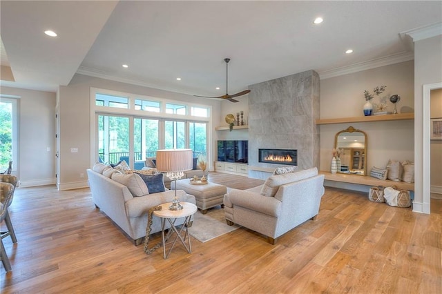 7736 N Donnelly Ave, Kansas City, MO 64158 - living area featuring light wood-style floors, recessed lighting, ceiling fan, a tiled fireplace, and ornamental molding