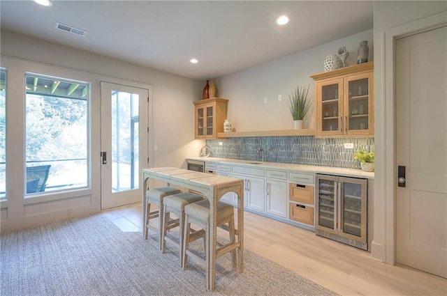 7736 N Donnelly Ave, Kansas City, MO 64158 - kitchen with beverage cooler, light countertops, tasteful backsplash, recessed lighting, and glass insert cabinets
