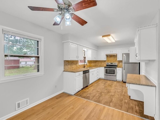 3717 S Hocker St, Independence, MO 64055 - kitchen with stainless steel appliances, tasteful backsplash, a ceiling fan, white cabinets, and light wood finished floors