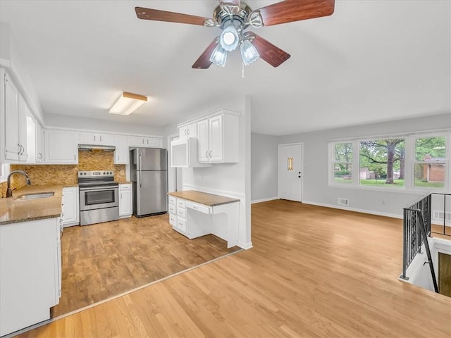 3717 S Hocker St, Independence, MO 64055 - kitchen featuring stainless steel appliances, ceiling fan, light wood-style flooring, white cabinets, and under cabinet range hood