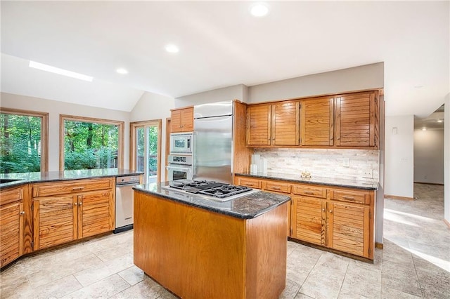 11909 Goddard St, Overland Park, KS 66213 - kitchen featuring built in appliances, vaulted ceiling, brown cabinets, tasteful backsplash, and a center island