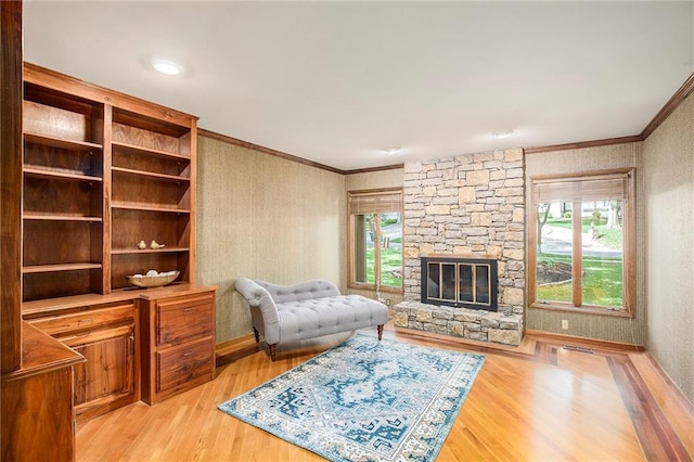 11909 Goddard St, Overland Park, KS 66213 - living room with wallpapered walls, crown molding, light wood-style floors, and a stone fireplace