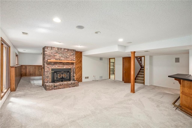 11909 Goddard St, Overland Park, KS 66213 - unfurnished living room with stairway, light carpet, a textured ceiling, a brick fireplace, and wooden walls