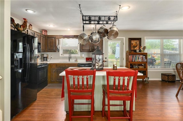 407 Maple Ct, Lansing, KS 66043 - kitchen featuring black appliances, dark wood-style floors, a kitchen island, light countertops, and dark brown cabinets