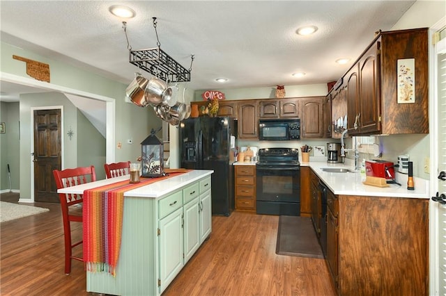 407 Maple Ct, Lansing, KS 66043 - kitchen with black appliances, a center island, wood finished floors, light countertops, and recessed lighting