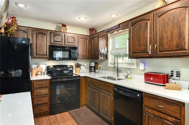 407 Maple Ct, Lansing, KS 66043 - kitchen featuring black appliances, light countertops, light wood finished floors, dark brown cabinets, and a textured ceiling