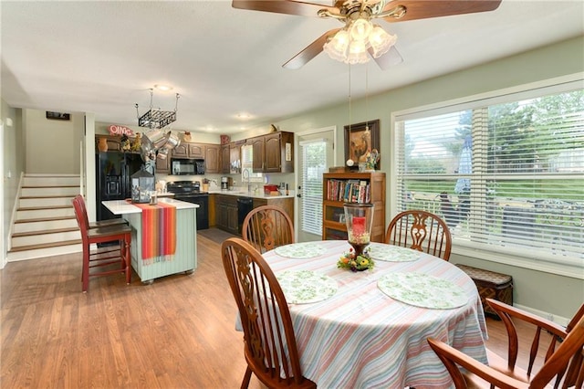 407 Maple Ct, Lansing, KS 66043 - dining area featuring light wood-style flooring, ceiling fan, and stairway