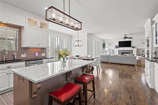 24957 W 98th St, Lenexa, KS 66227 - kitchen featuring stainless steel dishwasher, ceiling fan, backsplash, a fireplace, and glass insert cabinets
