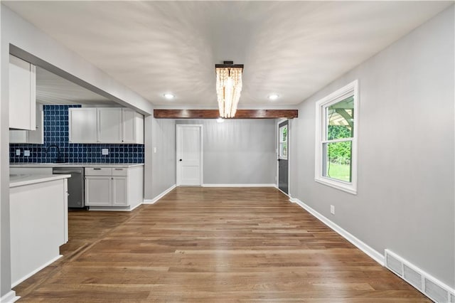 4301 W 74th St, Prairie Village, KS 66208 - kitchen with stainless steel dishwasher, light countertops, light wood finished floors, white cabinets, and decorative backsplash