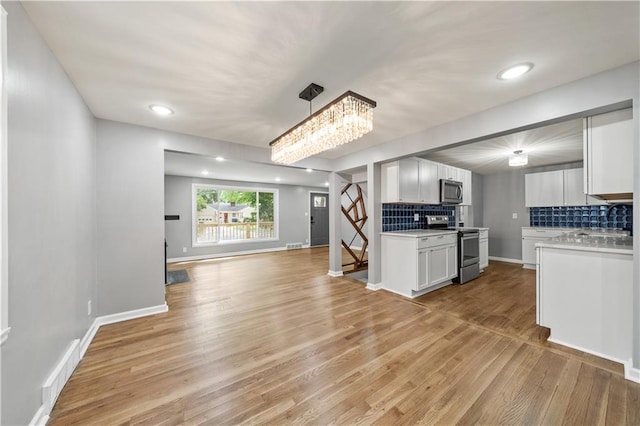 4301 W 74th St, Prairie Village, KS 66208 - kitchen with stainless steel appliances, open floor plan, light countertops, backsplash, and light wood-style floors