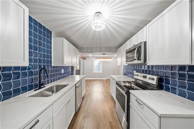 4301 W 74th St, Prairie Village, KS 66208 - kitchen featuring appliances with stainless steel finishes, light wood-type flooring, white cabinetry, backsplash, and a chandelier