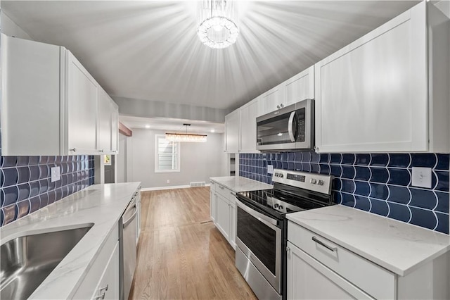 4301 W 74th St, Prairie Village, KS 66208 - kitchen with stainless steel appliances, a chandelier, light wood-style floors, and white cabinetry
