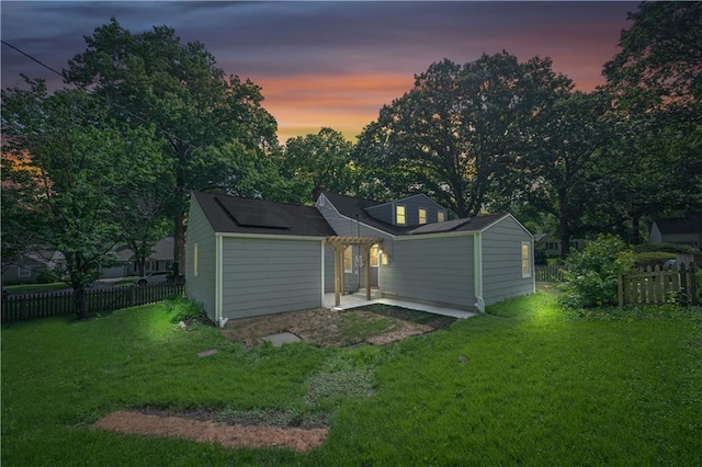 4301 W 74th St, Prairie Village, KS 66208 - back of house at dusk featuring roof mounted solar panels and a patio