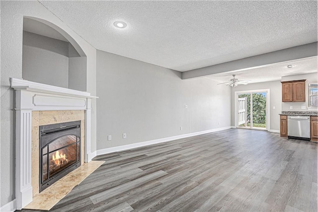 902 SW Peach Tree Ln, Blue Springs, MO 64064 - unfurnished living room with a textured ceiling, a fireplace, wood finished floors, and ceiling fan