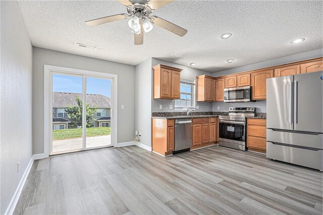 902 SW Peach Tree Ln, Blue Springs, MO 64064 - kitchen with appliances with stainless steel finishes, dark countertops, light wood finished floors, ceiling fan, and a textured ceiling