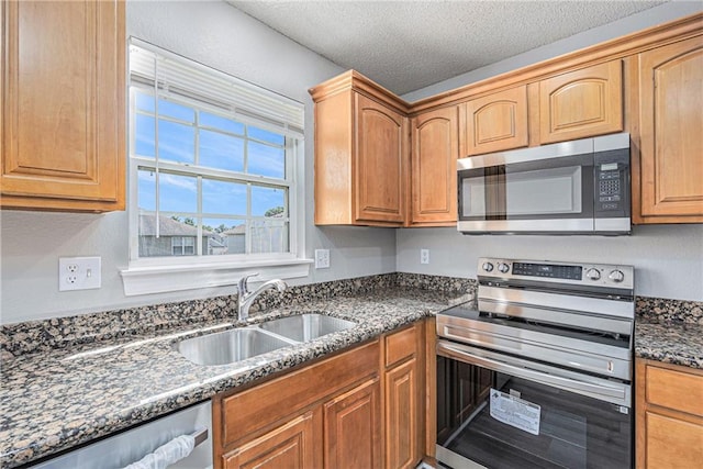 902 SW Peach Tree Ln, Blue Springs, MO 64064 - kitchen with appliances with stainless steel finishes, dark stone countertops, and a textured ceiling