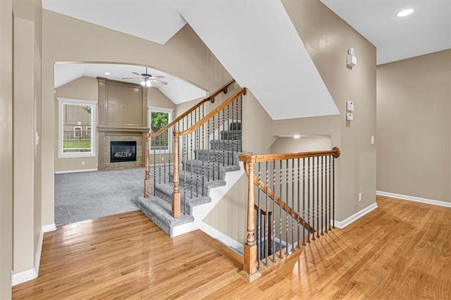895 N Diane Dr, Olathe, KS 66061 - staircase with a glass covered fireplace, ceiling fan, wood finished floors, arched walkways, and vaulted ceiling