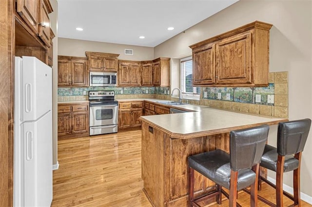 895 N Diane Dr, Olathe, KS 66061 - kitchen featuring stainless steel appliances, a peninsula, brown cabinets, light wood-type flooring, and recessed lighting