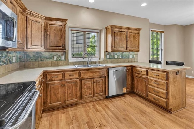 895 N Diane Dr, Olathe, KS 66061 - kitchen featuring appliances with stainless steel finishes, light wood finished floors, a peninsula, brown cabinetry, and recessed lighting